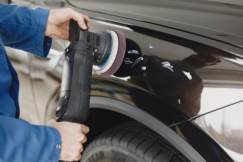 Panel beater sanding a repaired car body in an Auckland workshop
