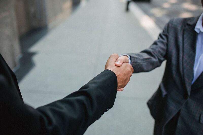 Insurance broker and Auckland business client shaking hands over a signed policy