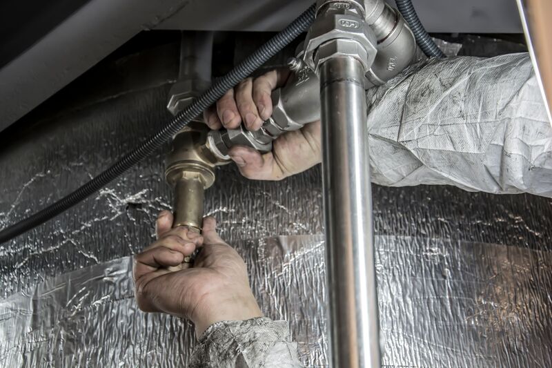 Auckland plumber fixing pipework under a sink
